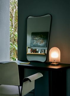 a desk with a chair, mirror and lamp on it