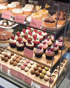 a display case filled with lots of different types of cupcakes and pastries