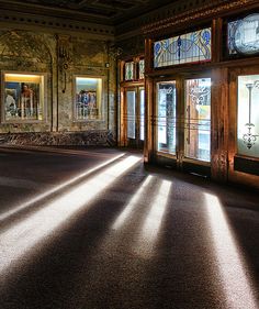 the sun shines through stained glass windows in an ornately decorated room with paintings on the walls