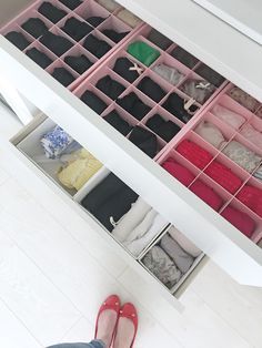 a person standing in front of an open drawer filled with clothes and slip - ons