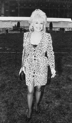 a woman walking across a grass covered field