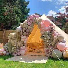 a teepee tent with balloons on the ground and some grass in front of it