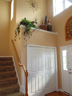 an entry way with two doors and a plant on the top shelf over the door