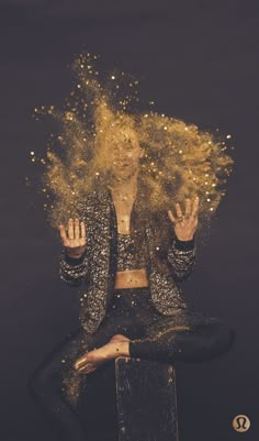 a woman sitting on top of a stool covered in gold dust