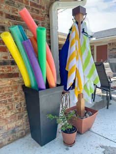 there are many different colored towels hanging on the outside of this house with potted plants next to it