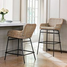 two wicker barstools sit in front of a counter with flowers on it