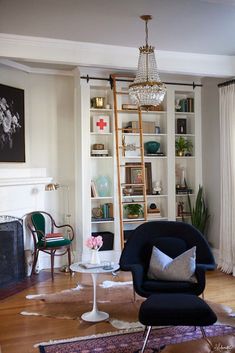 a living room filled with furniture and a chandelier hanging from the ceiling next to a fire place