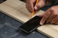 a man is writing on a piece of wood while holding a pencil in his hand