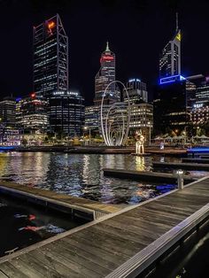 the city skyline is lit up at night with lights reflecting in the water and buildings