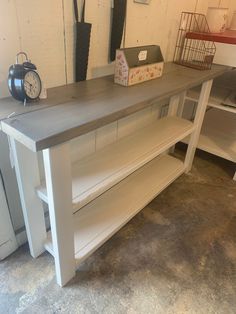 a wooden table with two shelves and an alarm clock on the wall next to it