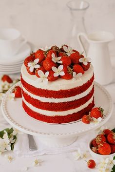 a red velvet cake with white frosting and fresh strawberries on top, surrounded by flowers