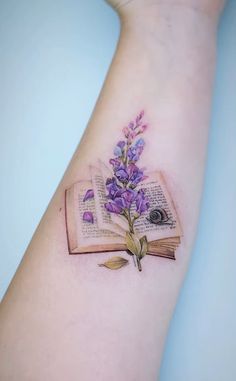 an open book with purple flowers on the arm