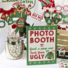 a table topped with lots of candy and christmas decorations next to a sign that says photo booth