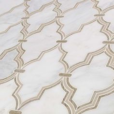 a marble table with an intricate design on it's surface, in white and gold