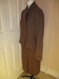 "This sharp suit is by Bert Newman for Suitime. It from from the late 1970's early 80's . It's 80% wool , 20% polyester. The jacket has 2 button side closure offset to one side with an interior snap. The skirt is a mock wrap with a center metal zipper and 2 buttons. The solid fabric is actually multi color tweed. I can see some plum and purple. The coordinating check fabric is on the collar and inside the skirt flap. The jacket has side pockets. No size tag but it is approx. size 2. The jacket m Notch Lapel Skirt Suit For Winter Business, Winter Business Skirt Suit With Notch Lapel, Tailored Notch Lapel Skirt Suit For Winter, Tailored Skirt Suit With Notch Lapel For Winter, Tailored Winter Skirt Suit For Business, Tailored Fall Skirt Suit With Buttons, Winter Formal Single-breasted Skirt Suit, Tailored Career Skirt Suit With Buttons, Winter Office Skirt Suit, Single Breasted