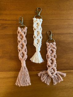 three crocheted key chains with tassels hanging from them on a wooden surface