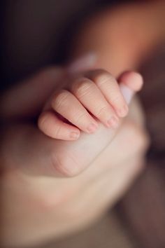 a baby's hand is held in the palm of someones hand with their thumb