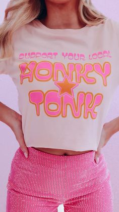 Supporting your local business is essential to your community so we thought this graphic tee was a good way to spread this message! This comfy oversized tee will be perfect styled with your fav denim for a trip to your local honky tonk for an evening of line dancing. We completed this look with our Rhianna Rhinestone Shorts - Bubble Gum Pink Features a light peach base, crew neck, short sleeves, with graphics of "Support Your Local Honky Tonk" in a yellow and pink font with a star in the middle. Trendy Summer T-shirt With Lettering, Trendy Summer Tops With Lettering, 90s Inspired Letter Print T-shirt For Spring, Rhinestone Shorts, Star Graphic, Honky Tonk, Line Dancing, Local Business, Light Peach