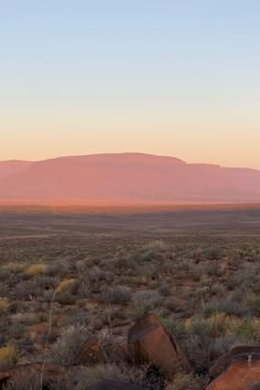 the sun is setting in the desert with mountains in the background