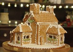 a gingerbread house with icing and decorations on the roof is sitting on a wooden platter