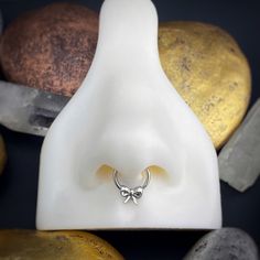 a nose ring with a bow on it sitting next to some rocks and other stones