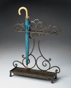 an umbrella is placed on top of a stand with wrought iron designs and holds a blue umbrella