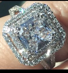 a close up of a person's hand holding an engagement ring