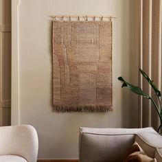 a living room with a chair and rug hanging on the wall