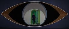 a man standing in front of an eye shaped mirror