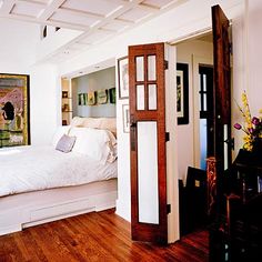 an open door leading to a bedroom with a bed in the corner and paintings on the wall