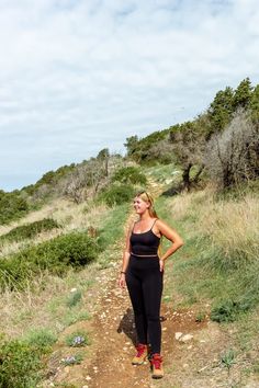 a woman is standing on a dirt path