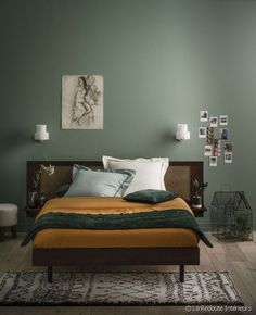 a bedroom with green walls and white pillows on the bed, along with pictures hanging on the wall