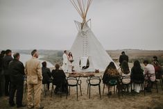 a group of people sitting around a table in front of a teepee