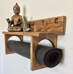 a wooden shelf with a buddha statue on it and a roll of yoga mat underneath