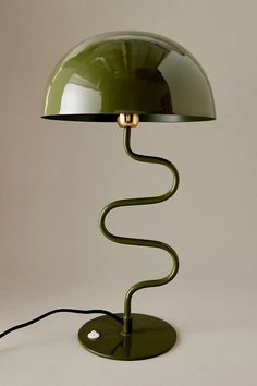 a green table lamp with a metal base and a light bulb on the end,