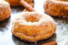 cinnamon sugar donuts on a baking sheet with cinnamon sticks