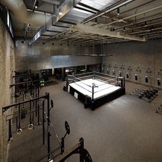 an empty boxing ring in a gym with benches and lights hanging from the ceiling above