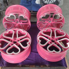 four pink wheels with hearts on them sitting on a purple cloth