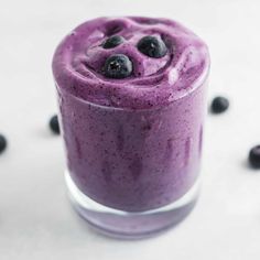 a blueberry smoothie in a glass surrounded by blueberries