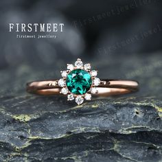 a close up of a ring with a green stone in the center on a rock