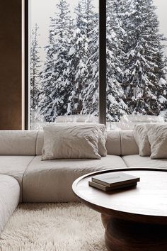 a large white couch sitting in front of a window next to a table with a remote control on it