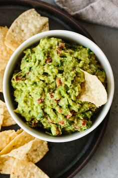 a bowl filled with guacamole surrounded by tortilla chips