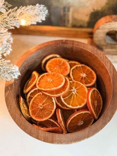 a wooden bowl filled with sliced oranges on top of a table