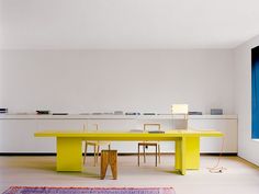 a yellow table and chairs in a white room with blue window sill on the wall