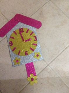 a pink and silver clock on the floor with flowers painted on it's face