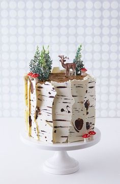 there is a cake that has been decorated with trees and deers on the top