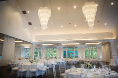 a banquet room set up with white linens and chandeliers