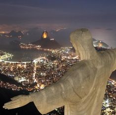 a statue is overlooking the city lights and mountains at night in rio de oro, brazil