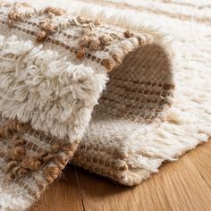 a close up of a rug on the floor with wood grains and white fabric