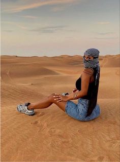 a woman sitting on top of a sandy dune